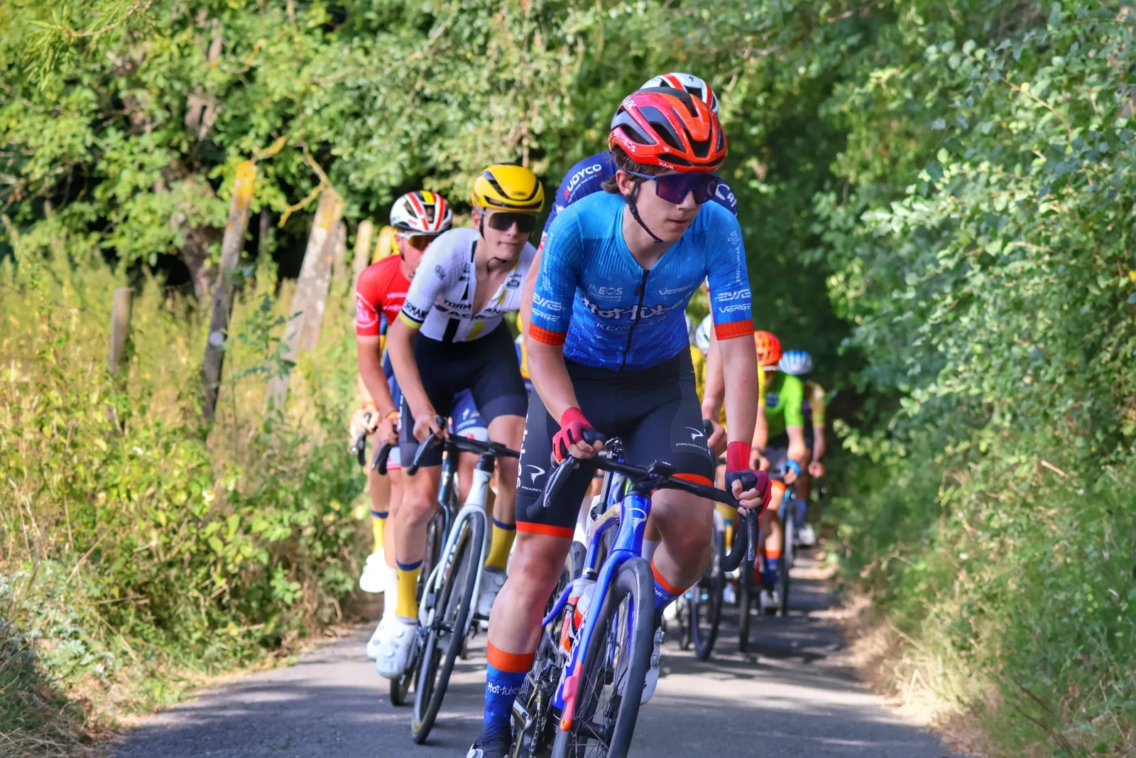 Devin riding at the front of a group on a narrow country road
